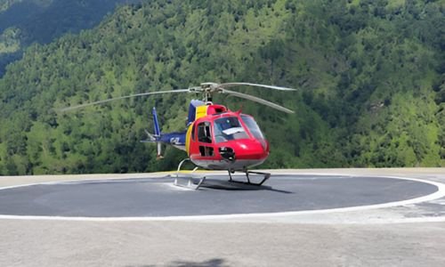 Red helicopter parked at the Sersi helipad, ready for the Kedarnath helicopter journey.